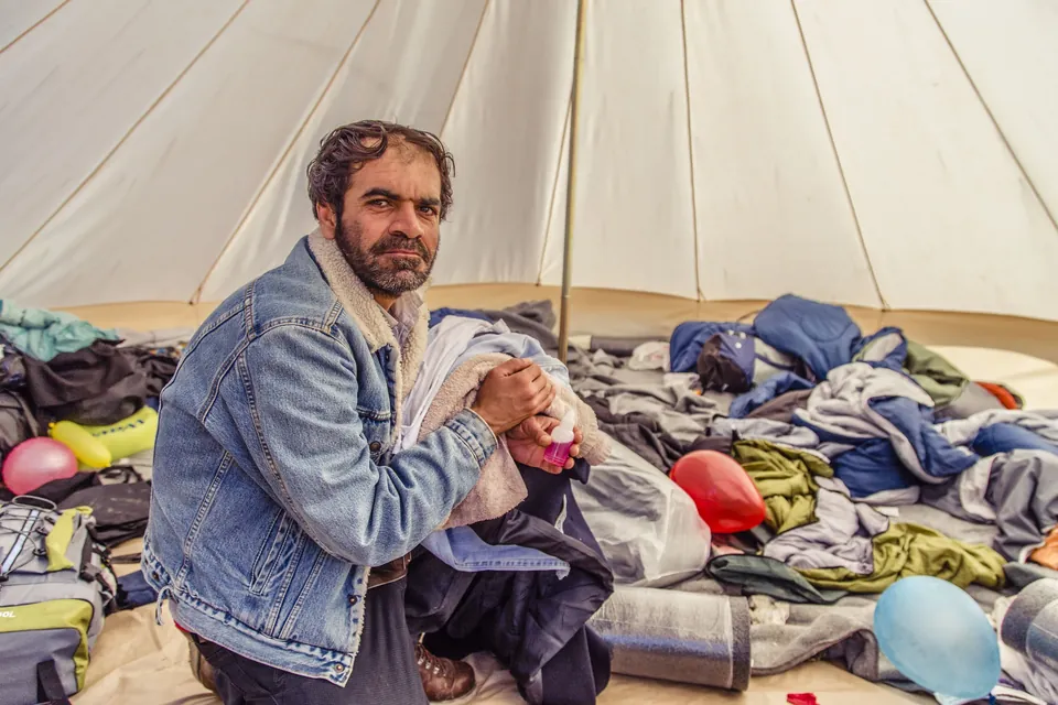 A man sits among donated clothing inside a tent in Greece