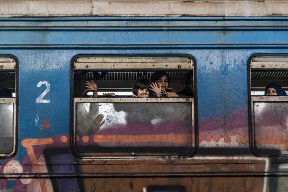 Refugees look out from the windows of a train in Šid, Serbia