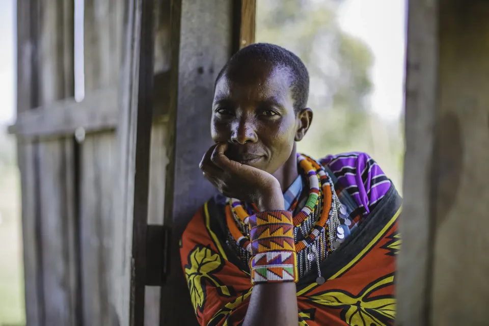 A Maasai woman in beaded jewelry rests her chin on her hand